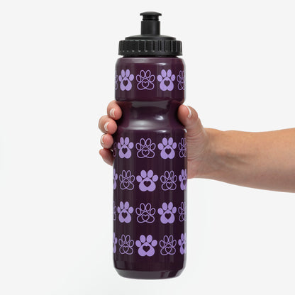 Hand holding a purple water bottle decorated with paw print patterns.