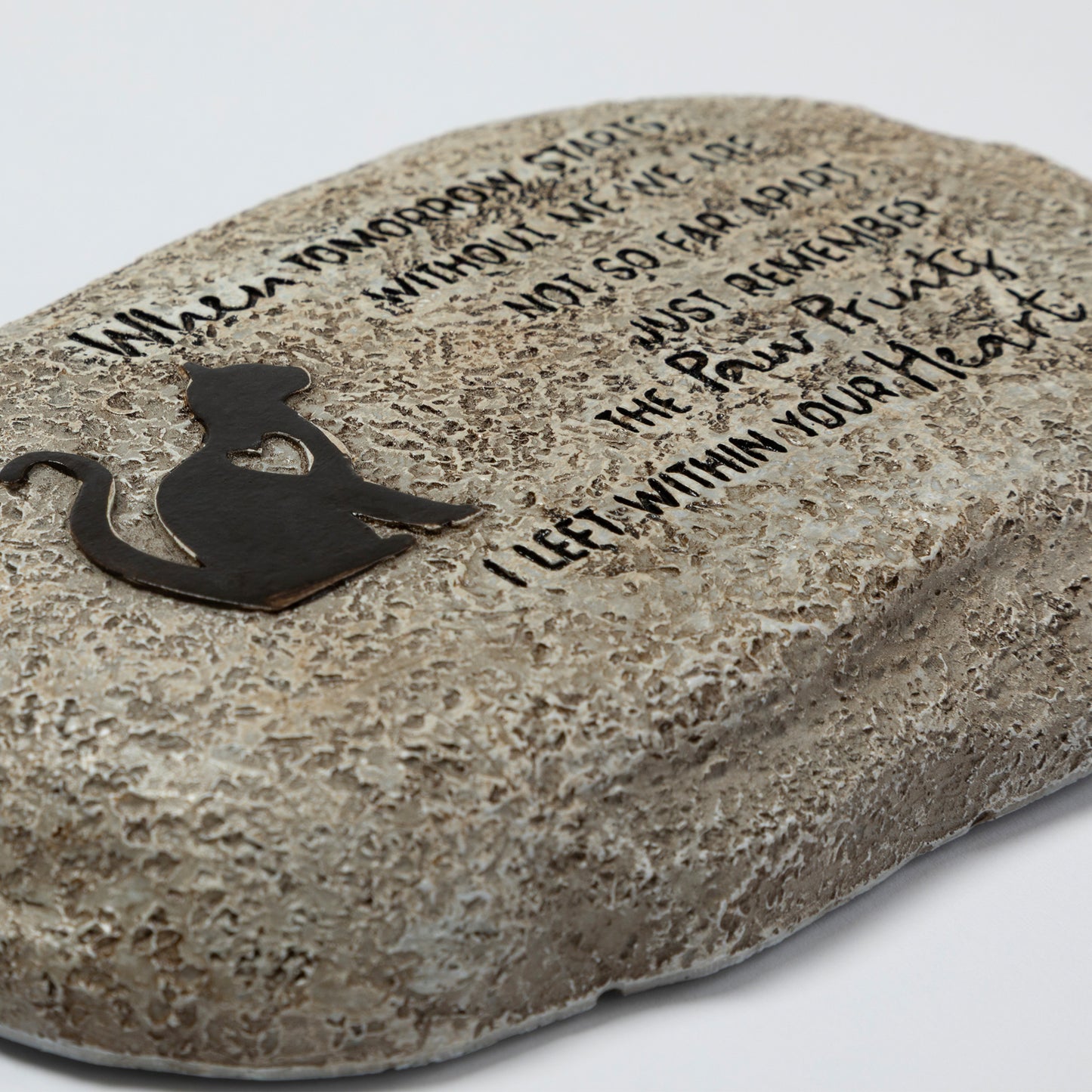 Decorative stone with engraved text and a cat silhouette on a light gray background