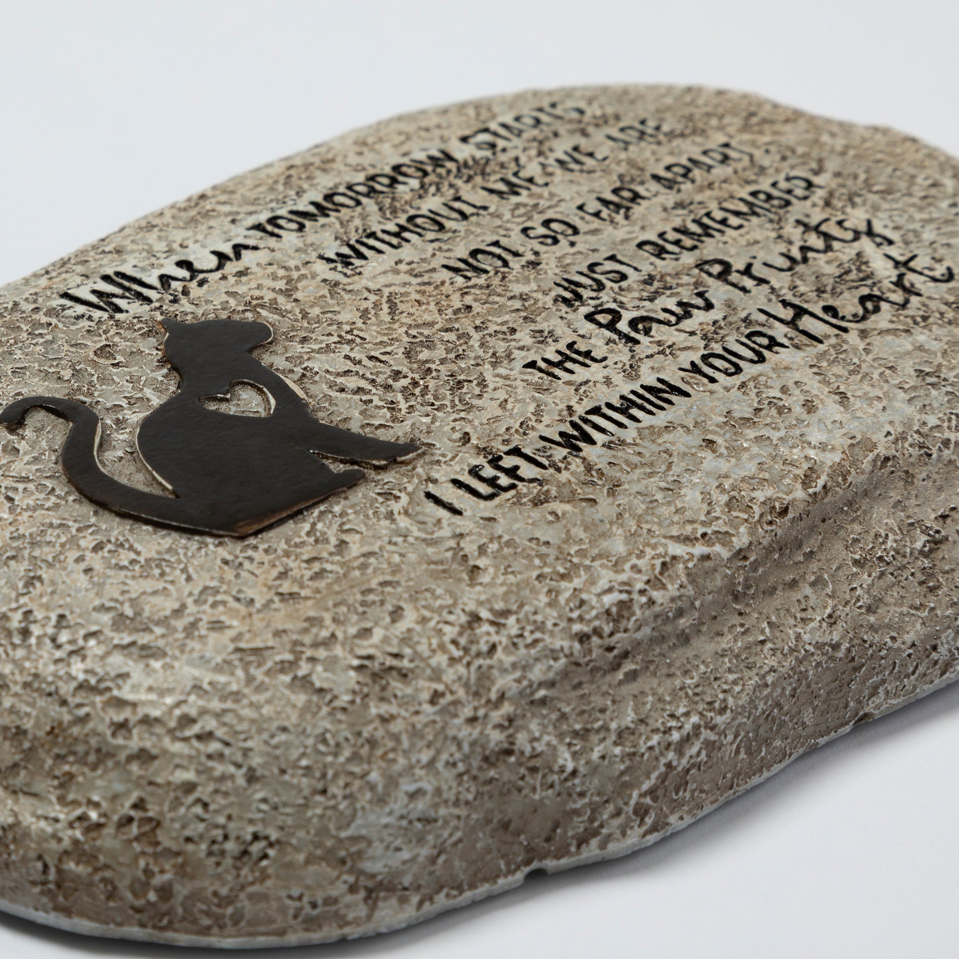 Decorative stone with engraved text and a cat silhouette on a light gray background