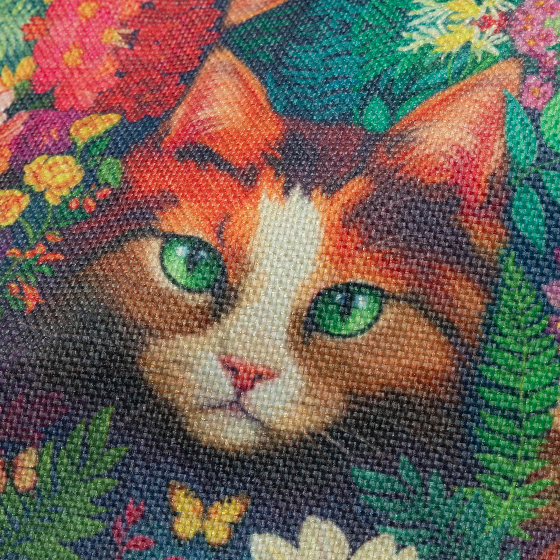 Close up of woven bag featuring a cat's face with floral and butterfly details