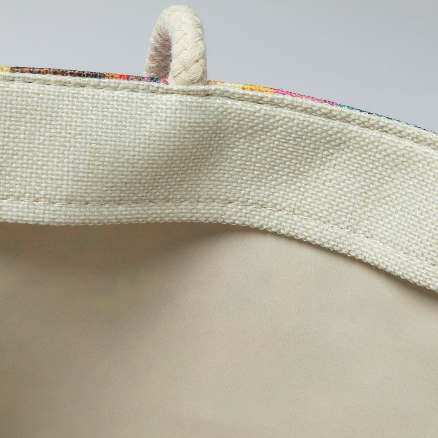 Close-up of a textured fabric strap with a colorful border on a neutral background