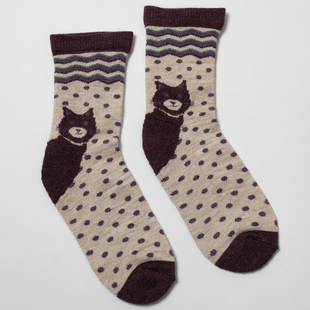 A pair of crew socks with a beige base, dark brown polka dots, a dark brown cat graphic, and a dark brown and gray patterned cuff, shown on a light gray background.