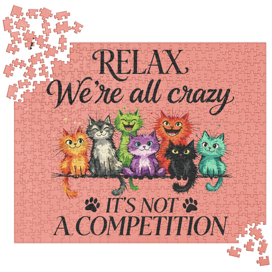 A completed jigsaw puzzle featuring a pink background with the text 'RELAX We're all crazy' and 'IT'S NOT A COMPETITION' in black script. Colorful cartoon cats sit on a branch across the center, and a few loose puzzle pieces are scattered around the corners.