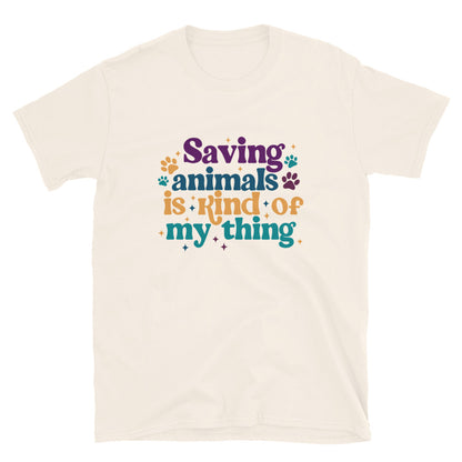 tan shirt that reads Saving Animals is kind of my Thing with several paw print and sparkle images in a purple, yellow and blue font.