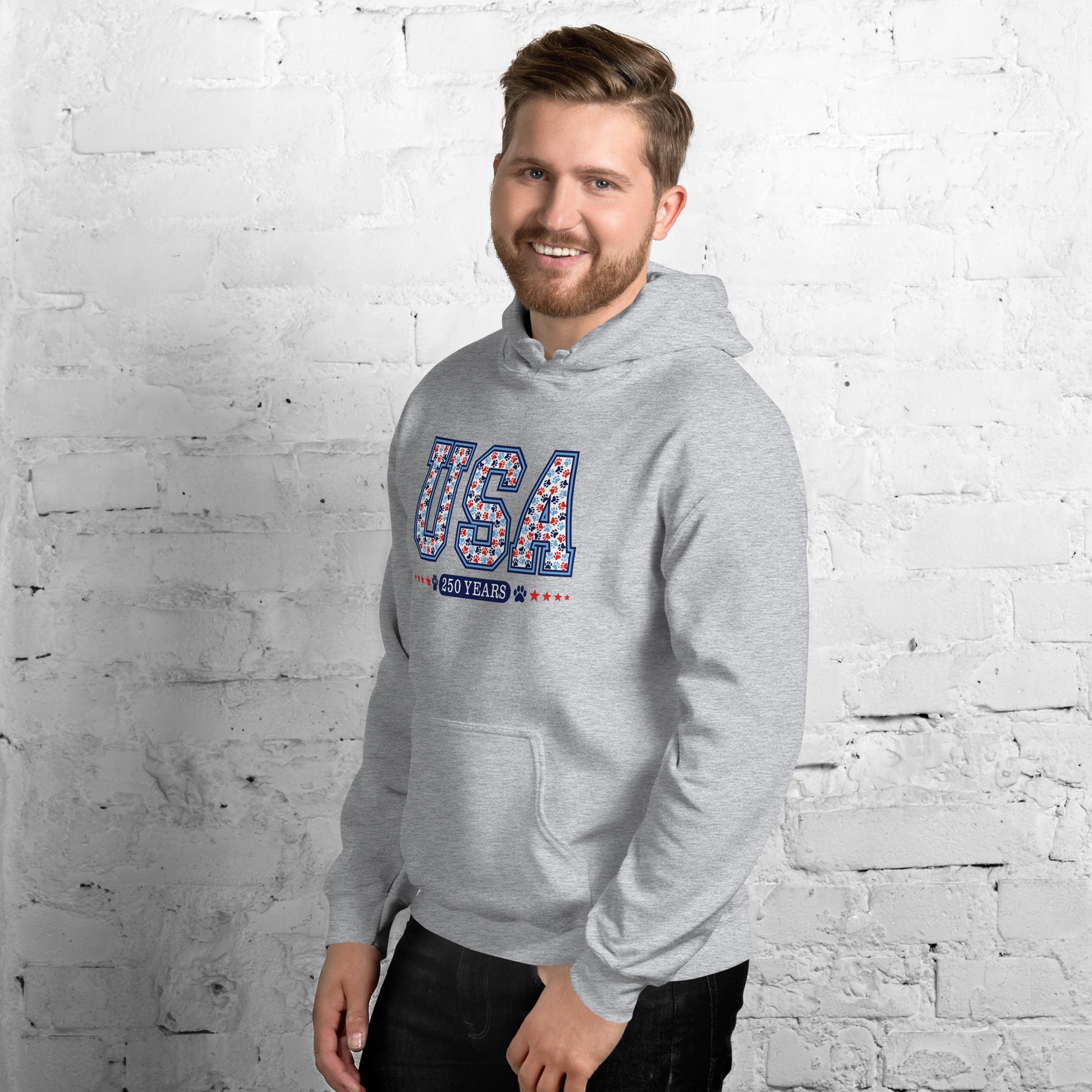 Man wearing a gray hoodie with colorful text against a white brick wall.