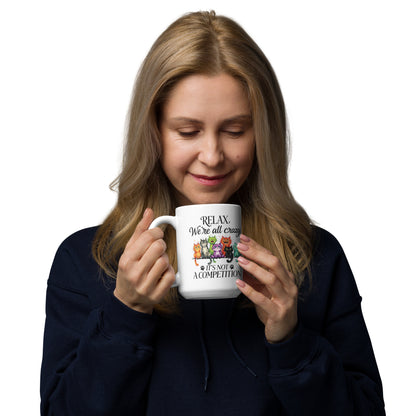 Woman smiling, holding a white mug with image of 7 cats on it, on a white background