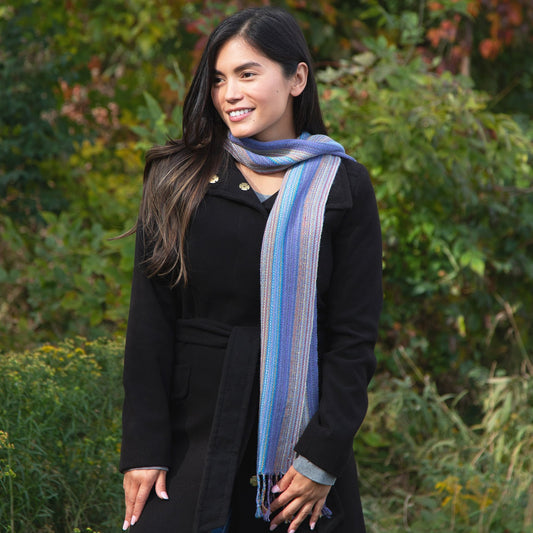 A woman wearing a black peacoat with a multicolored, striped alpaca fiber scarf with fringes.